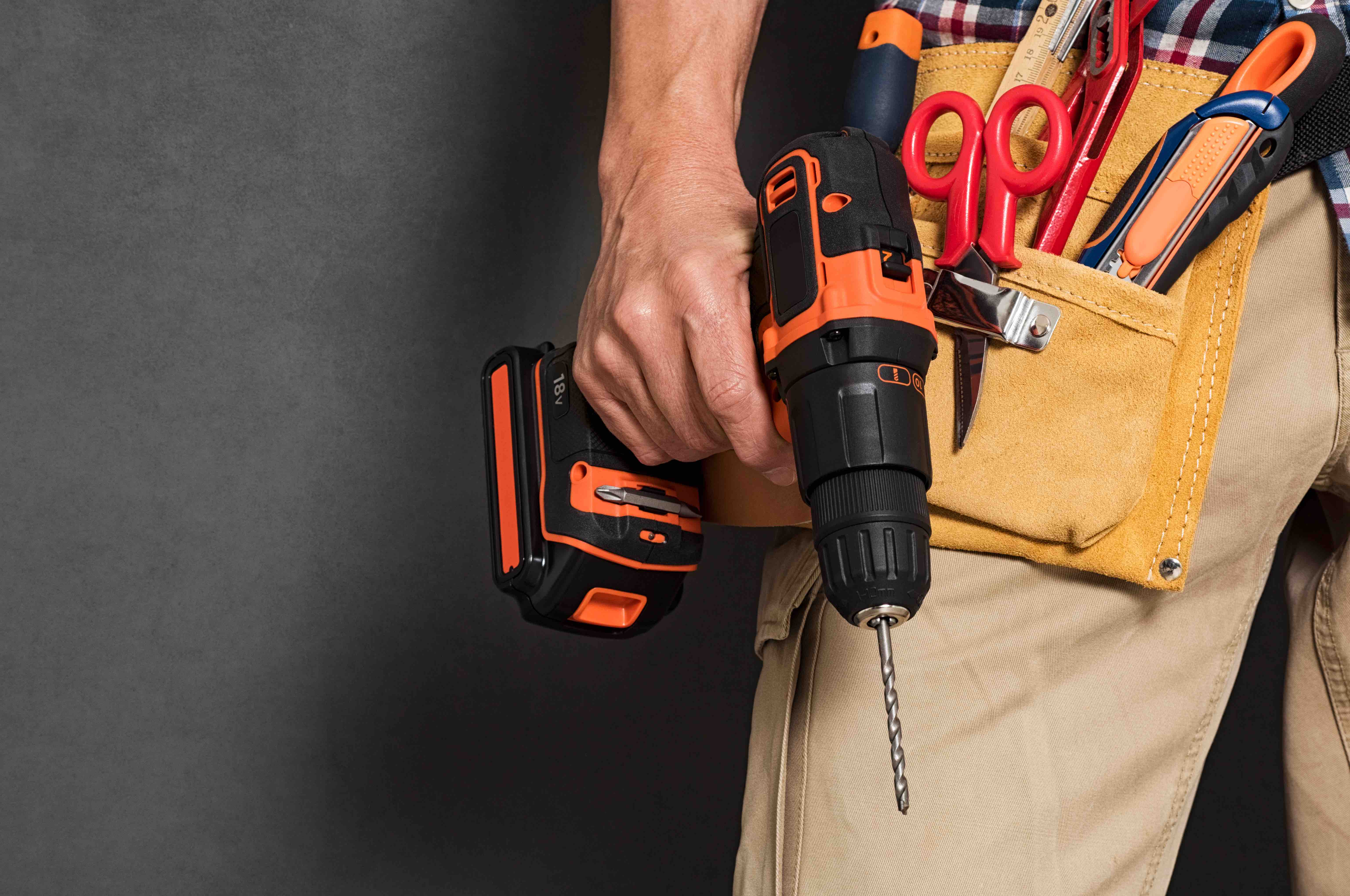 handyman contractor with tool belt holding electric drill for construction