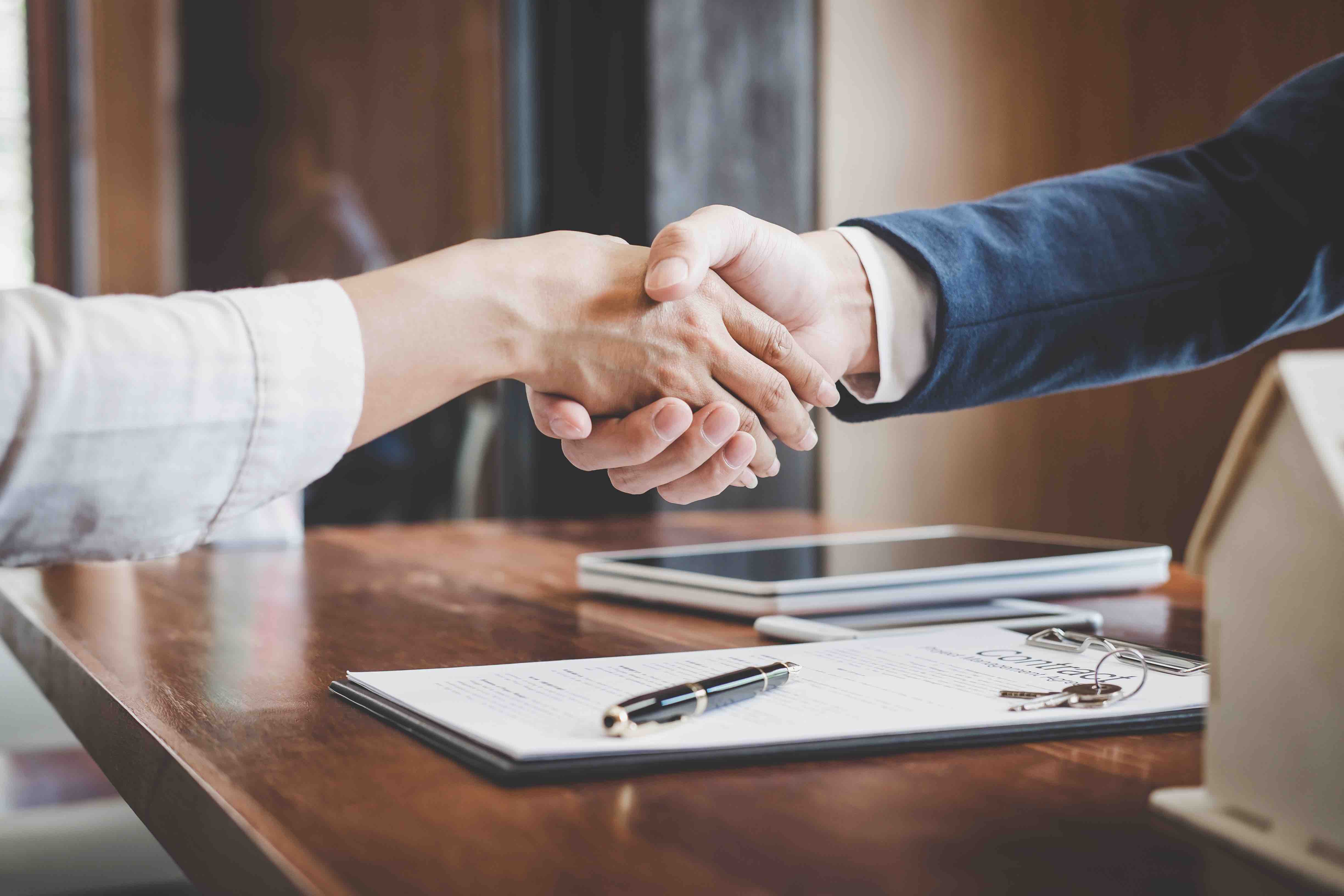 man and woman shaking hands after signing business insurance policy